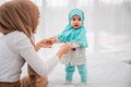 Happy muslim young mother and adorable little baby daughter in hijab on white bed in bedroom at home. Muslim mom hands holding Royalty Free Stock Photo