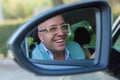 Happy with my car choice. Portrait young man driver reflection in car side view mirror. Guy driving his new car. Positive human Royalty Free Stock Photo