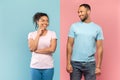 Happy mysterious black couple looking at each other and smiling, standing isolated over halved pink and blue wall Royalty Free Stock Photo