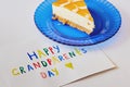 Happy National Grandparents day. Colored greeting card made by children and piece of cake on blue plate as gift