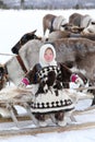 Happy Nenets girl in national clothes among the Northern domestic reindeer