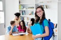 Happy nerdy female student with eyeglasses and group of international students