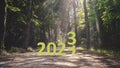 Happy New Year 2023 concept with years transition text on forest road.
