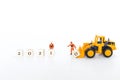 Miniature worker moving wooden cube with yellow front end loader truck Royalty Free Stock Photo