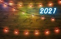 2021 happy new year background. Neon numbers 2021 and garlands with lights on wooden background.