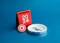 3d Target icon, 2024 numbers year on red desk calendar cover stand and compass on blue background.