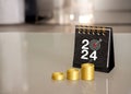 Gold coin stacked as a graph with rise arrow and 2024 numbers with target icon on black small desk calendar. Royalty Free Stock Photo