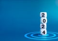 2024 Happy New year banner. 2024 year numbers on white dice cube blocks stacked on target dart icon on blue background.