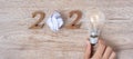 2020 Happy New year with Businessman holding lightbulb with crumbled paper and wooden number on table. New Start, Idea, Creative,