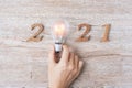2021 Happy New year with Businessman holding lightbulb with and wooden number on table. New Start, Idea, Creative, Innovation,