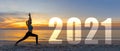 Happy new year card 2021. Silhouette lifestyle woman yoga practicing yoga standing as part of Number 2021 near the beach at sunset Royalty Free Stock Photo