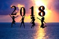 Happy new year card 2018. Silhouette young woman jumping on tropical beach over the sea and 2018 number with sunset background Royalty Free Stock Photo