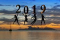 Happy new year card 2019. Silhouette young woman jumping on tropical beach over the sea and 2019 number with sunset background Royalty Free Stock Photo