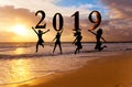 Happy new year card 2019. Silhouette young woman jumping on tropical beach over the sea and 2019 number with sunset background Royalty Free Stock Photo