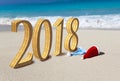 Happy new year card. Two New Year`s caps of Santa Claus on beach and inscription 2018 in the sand Royalty Free Stock Photo