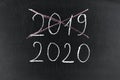Happy new year 2020. Chalkboard with 2020, crossed 2019 and hand with chalk Royalty Free Stock Photo