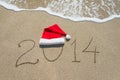 Happy new year 2014 with christmas hat on sandy beach - holiday Royalty Free Stock Photo