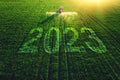 2023 Happy New Year agricultural business concept. Aerial view of farming tractor plowing and spraying on green field