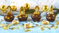 Happy new year 2024 concept. Bright candles, chocolate muffins, Christmas tree toys, balls and golden confetti Royalty Free Stock Photo