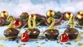 Happy new year 2024 concept. Bright candles, chocolate muffins, red Christmas balls and golden confetti Royalty Free Stock Photo