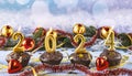 Happy new year 2024 concept. Burning candles, chocolate muffins, red Christmas balls and golden confetti Royalty Free Stock Photo