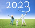 Happy New year 2023 concept. Happy family watching the cloud drawing by airplane in sky