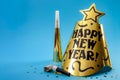 Happy new year concept with a festive hat, noisemakers, confetti, party blower and paper trumpet isolated on blue background with