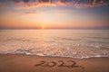 Happy New Year 2022 concept, lettering on the beach. Written text on the sea sand at sunrise Royalty Free Stock Photo