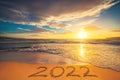 Happy New Year 2022 concept, lettering on the beach sand. Sea sunrise. Royalty Free Stock Photo