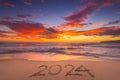 Happy New Year 2024 concept, lettering on the beach. Written text on the sea beach at sunrise