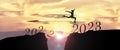 2023 Happy New Year concept, Young woman Jumping across the gap of the mountain from Old year 2022 to 2023 New Year Royalty Free Stock Photo