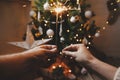 Happy New Year! Couple celebrating with firework lights against christmas tree and glowing star