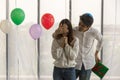 Happy New Year and couple concept. Asian young man surprise and close woman eye by right hand and holding green gift box behide
