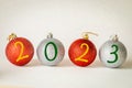 Happy New Year 2023, Creative concept, Christmas beautifully shiny Christmas baubles with New Years date, cream background