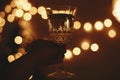 Happy New Year eve party. Hand holding champagne glass on background of golden christmas lights, celebrating and toasting in dark Royalty Free Stock Photo