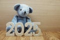 Happy New Year 2025 festive background with teddy bear decoration on wooden background