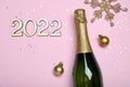 Happy New Year 2022! Flat lay composition with bottle of sparkling wine on pink background, space for text Royalty Free Stock Photo