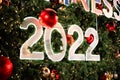 Happy New Year 2022 glowing on christmas tree and ornament balls