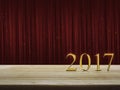 Happy new year 2017 gold metal text on table over red curtain