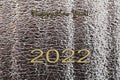 Happy New Year 2022 in gold numeral with Happy New Year handwriting on a silver aluminum background with reflection