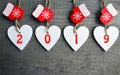 Happy New Year greeting card.Decorative white wooden Christmas hearts and red mittens with 2019 numbers on old wooden background. Royalty Free Stock Photo