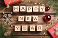 Happy New Year greeting card. Phrase made with cubes and festive decor on wooden background, flat lay