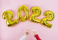 Happy New Year 2022. Hands with glasses toasting on pink background. Copy space Royalty Free Stock Photo