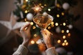 Happy New Year! Hands holding burning sparkler and champagne glass against christmas tree lights Royalty Free Stock Photo