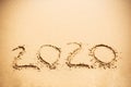 Happy New Year 2020, handwritten on sandy beach. 2020 numbers inscription on golden sand at sea beach. Tropical celebration Royalty Free Stock Photo