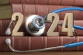 2024 Happy New Year for health care medicine and pharmacy industry. Number 2024 with stethoscope on vintage books of medicine