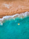 Happy New Year 2021, lettering on the beach with wave and blue sea. Numbers 2021 year on the sea shore, New Years concept