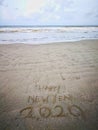 Happy new year 2020, lettering on the beach with wave and clear blue sea. Numbers 2020 year on the sea shore. Royalty Free Stock Photo