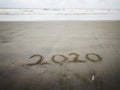 Happy new year 2020, lettering on the beach with wave and clear blue sea. Numbers 2020 year on the sea shore. Royalty Free Stock Photo