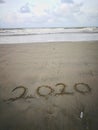 Happy new year 2020, lettering on the beach with wave and clear blue sea. Numbers 2020 year on the sea shore. Royalty Free Stock Photo